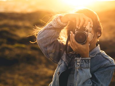 Beautiful woman taking picture outdoors with a analog camera